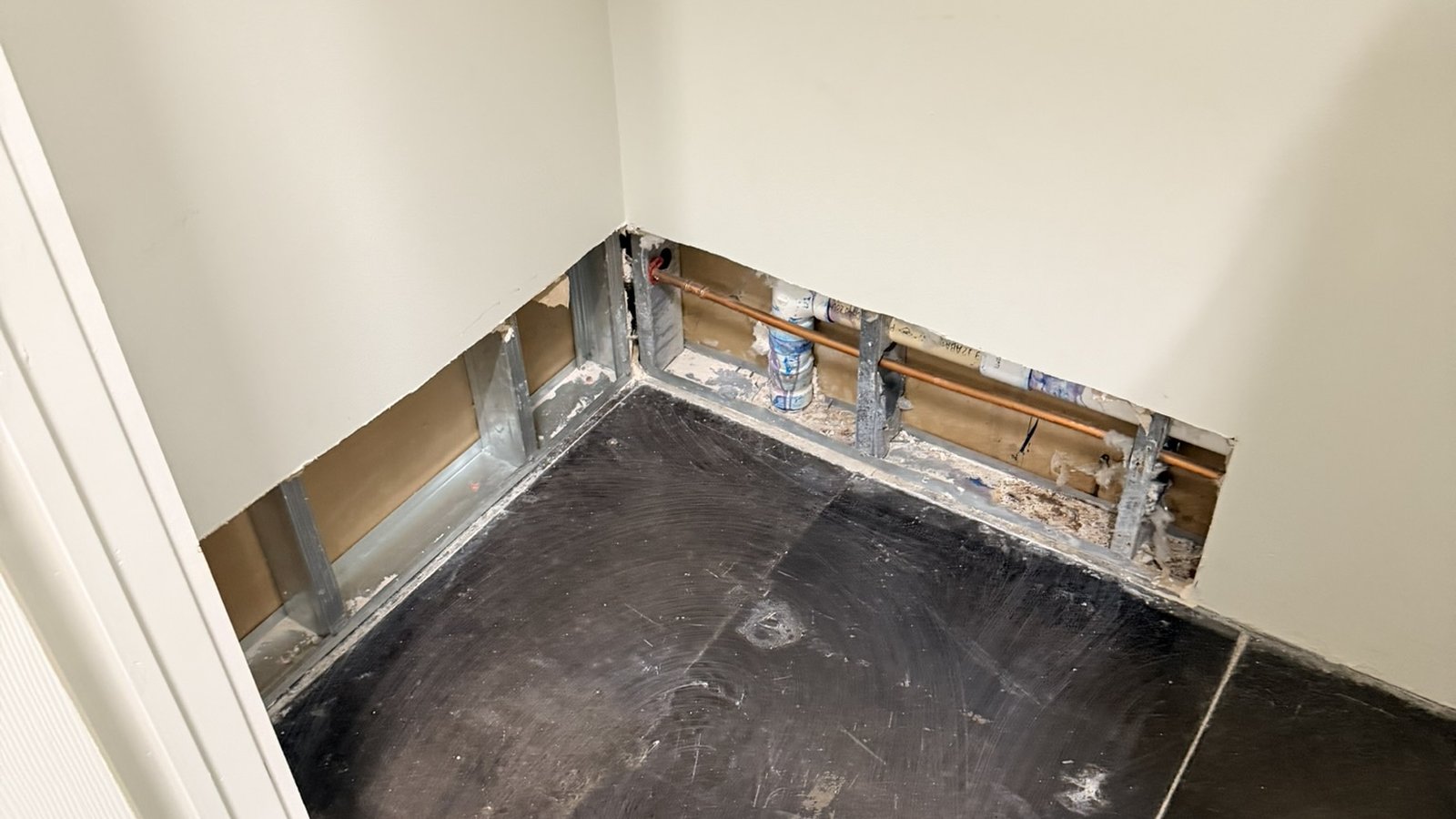 Wall opened at the base, showing a copper water line in the cavity