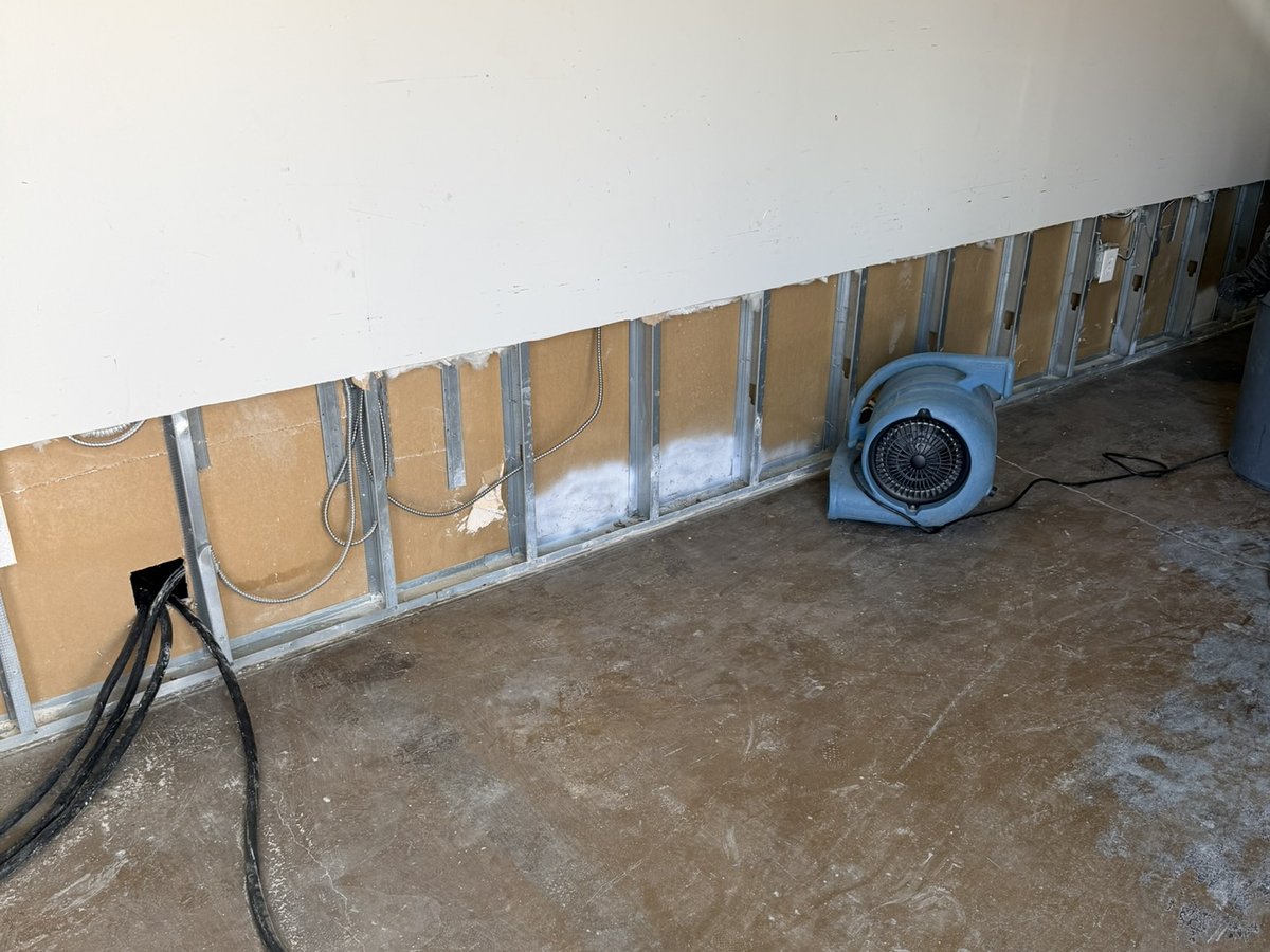 Drywall cut above the floor with an air mover drying the wall cavity