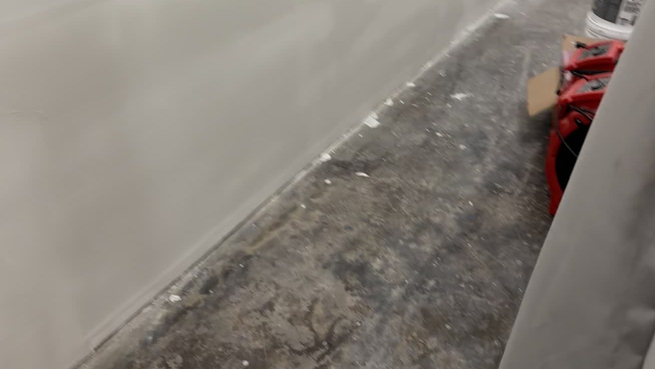 Corridor wall base after a flood cut, air mover drying the slab