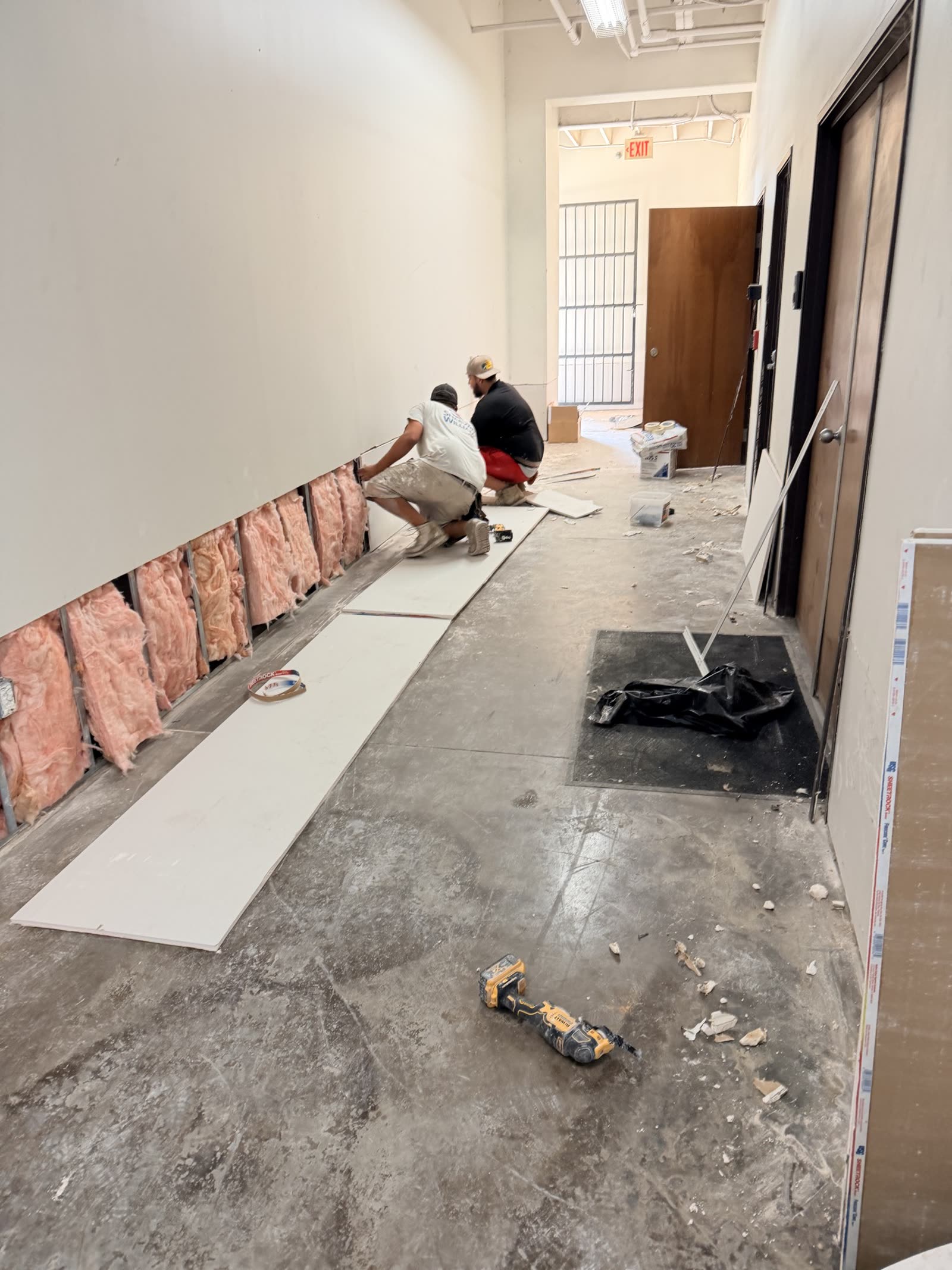 Fort Worth — crew hanging drywall at the base of a commercial corridor