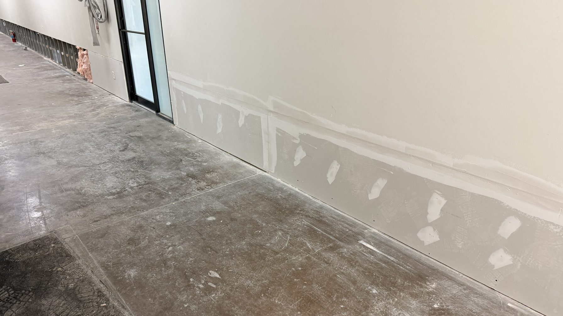 Flood-cut drywall patched along a shared corridor after a water loss