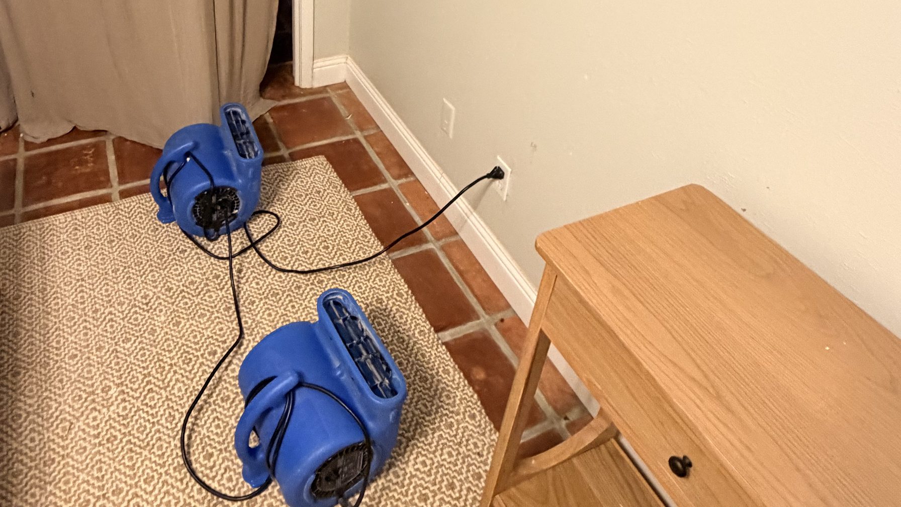 Two air movers drying a lived-in room with the furniture still in place