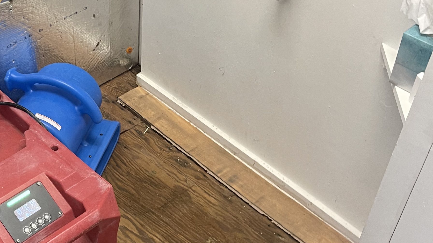 Dehumidifier and air mover drying a water-stained wood floor